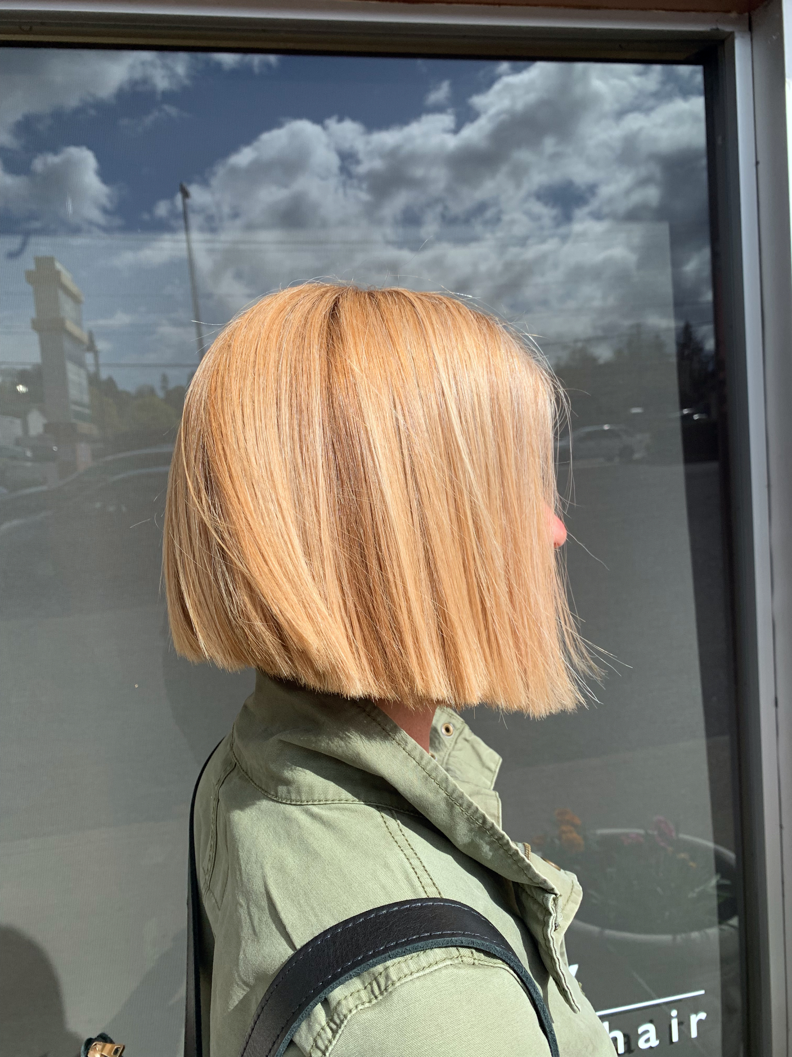 Client with a blunt, golden blonde bob seen in profile in front of the willow hair salon window